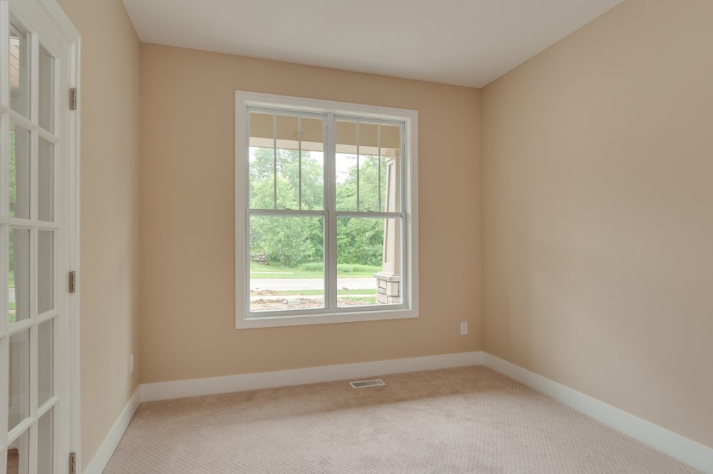 A bedroom with a large window and carpet.