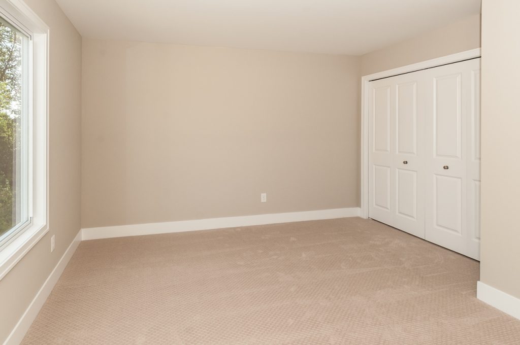 A room with a door open and a white wall.