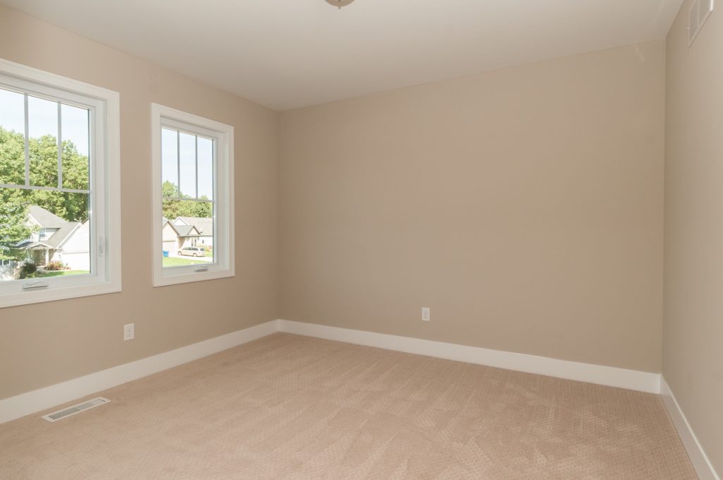 A room with tan walls and beige carpet.