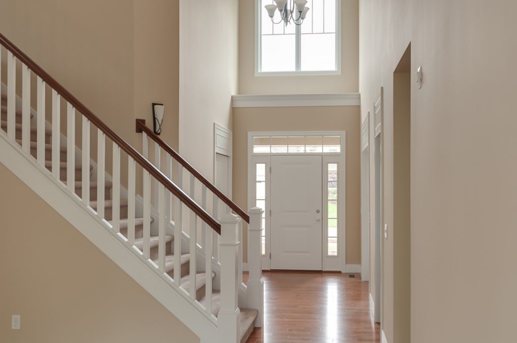 A large hallway with a white staircase and wooden floor.