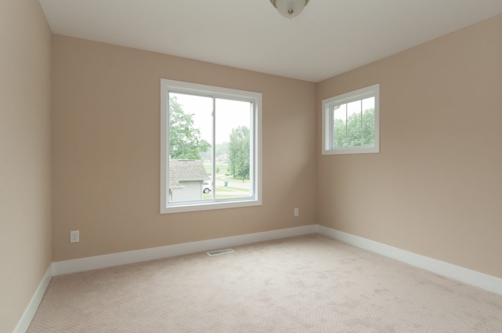 A room with two windows and a carpet.