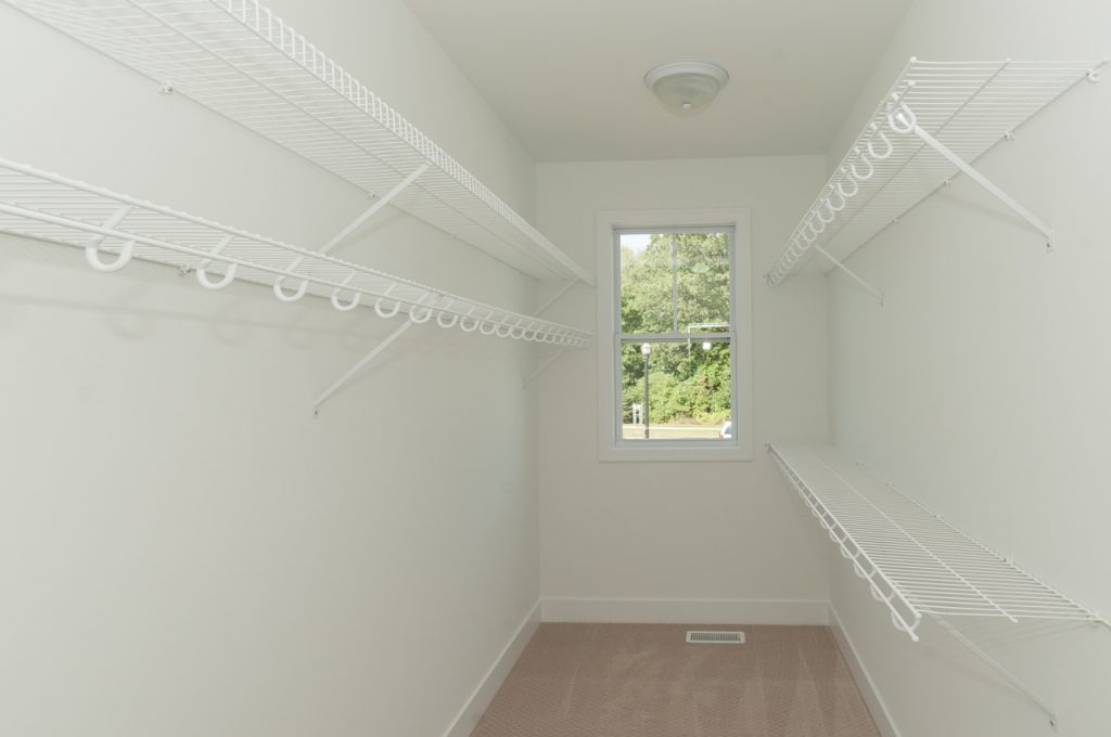 A white room with many shelves and a window.