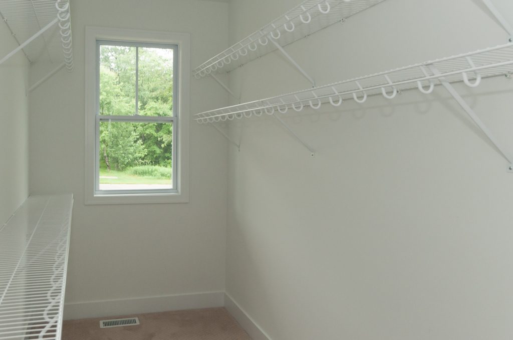 A room with two white shelves and a window.