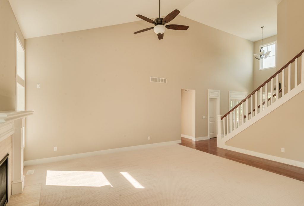 A large room with a ceiling fan and hardwood floors.