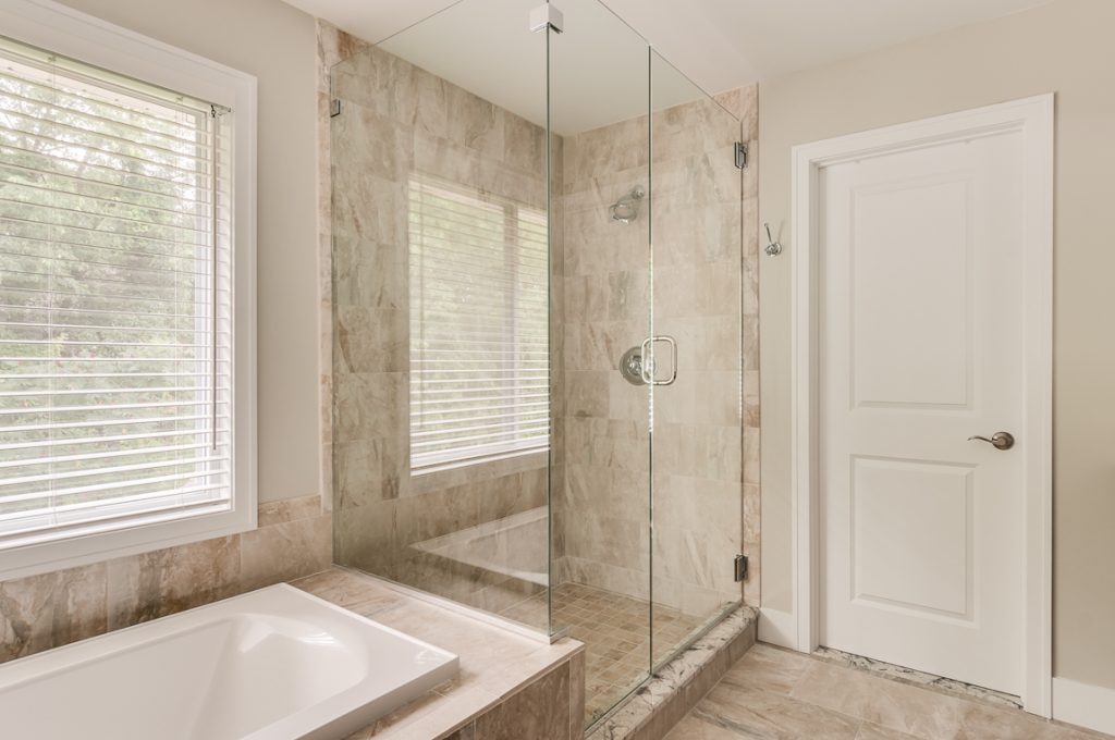 A bathroom with a large glass shower and a tub.