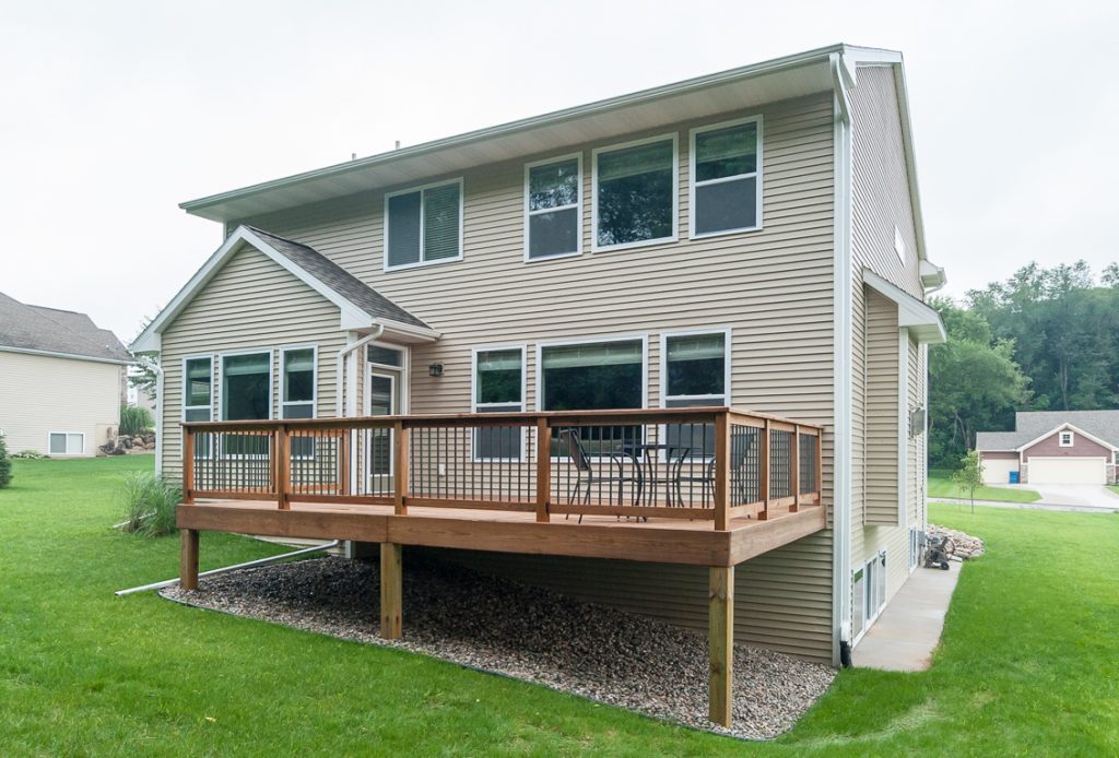 A large deck with a wooden railing and a lawn.