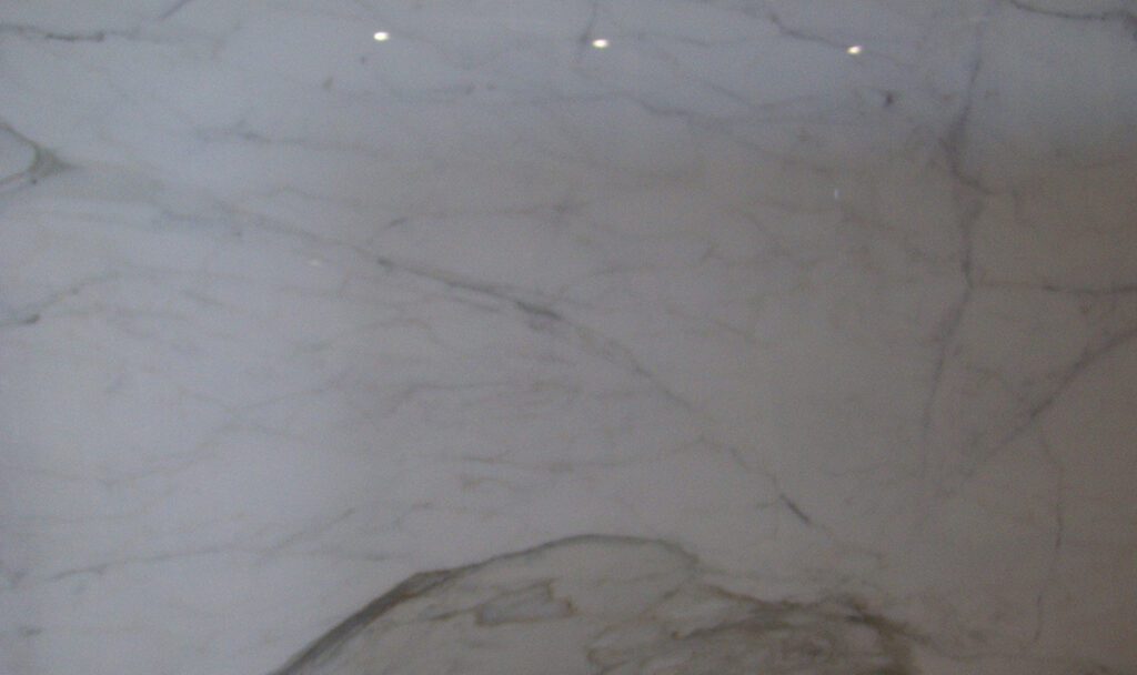 A white marble wall with lights on the ceiling.