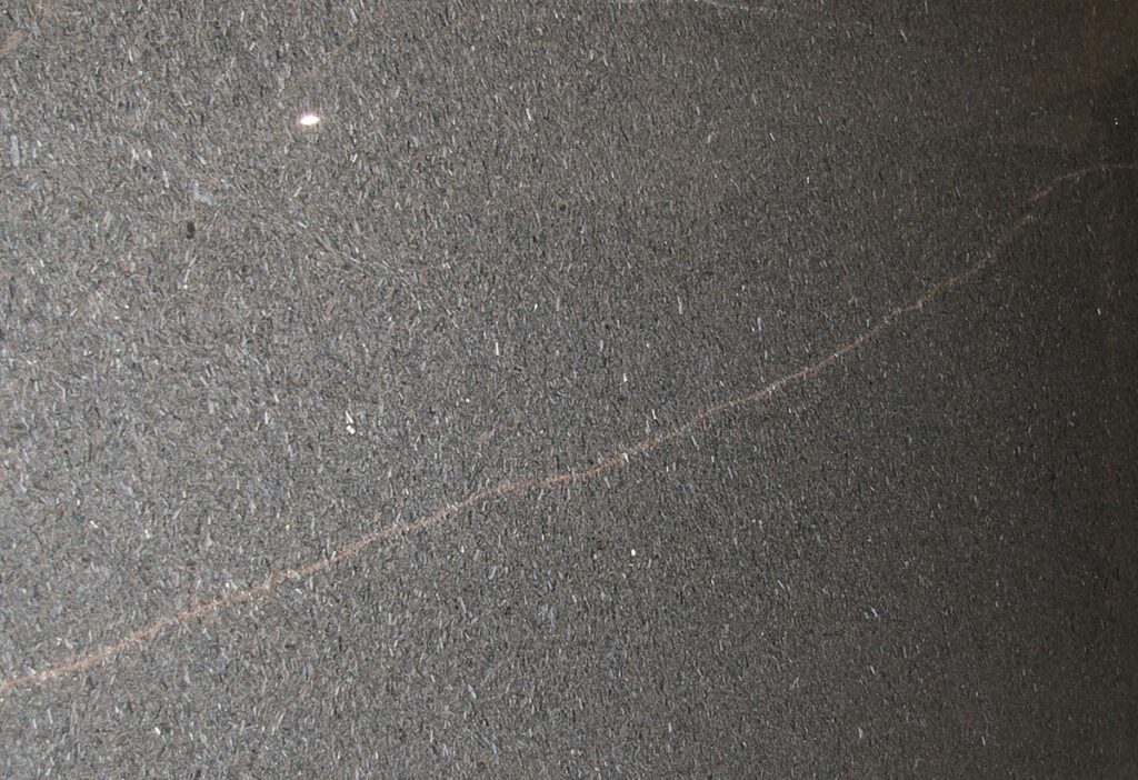 A close up of the surface of a black stone floor.
